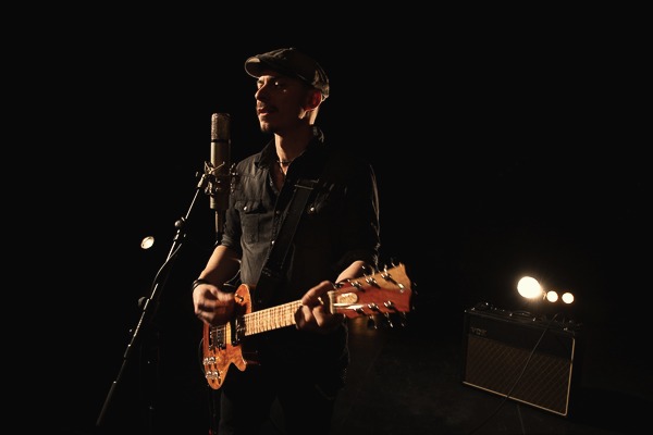 Nico Sarro chante et joue de la guitare au micro